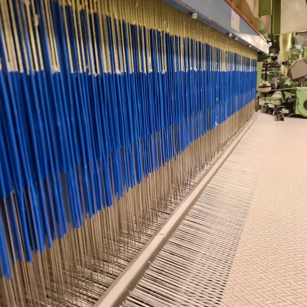Blue and natural warp threads on a John England loom in Banbridge